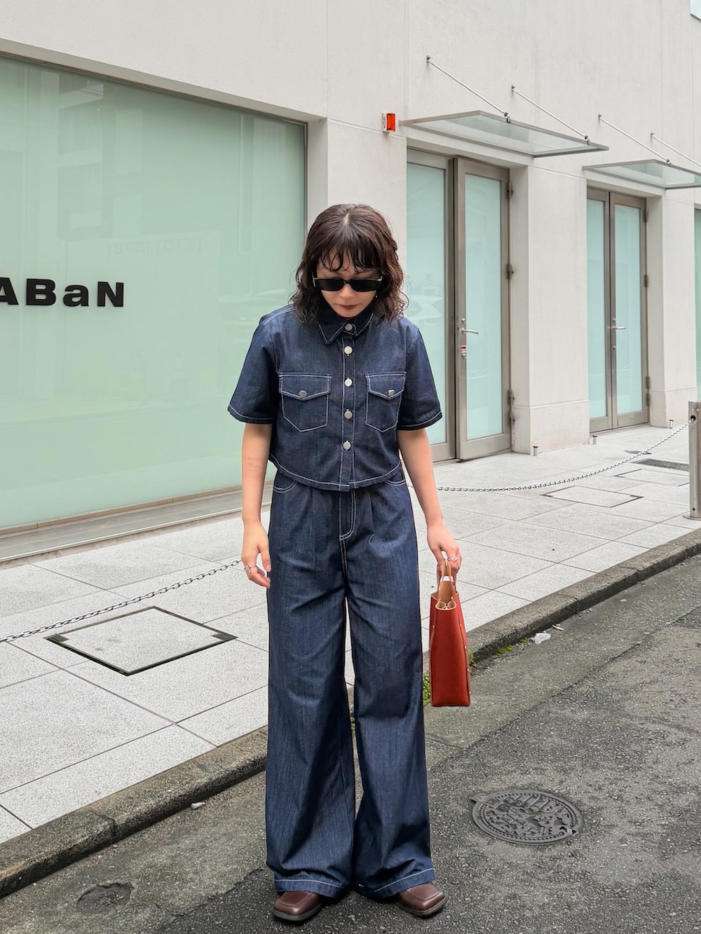 ブルー系のトップス、オレンジ系のバッグ、ブルー系のパンツを着用したレディースの夏コーディネートの2枚目の写真