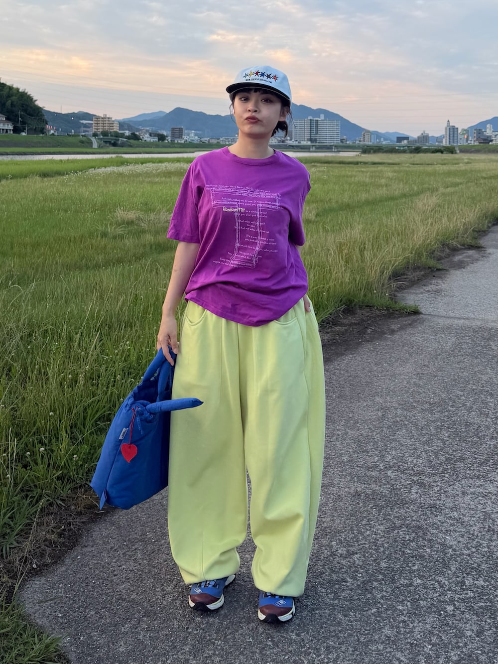 ブルー系のハンドバッグ、パープル系のTシャツ/カットソー、イエロー系のスウェットパンツを着用したレディースの夏コーディネートの2枚目の写真