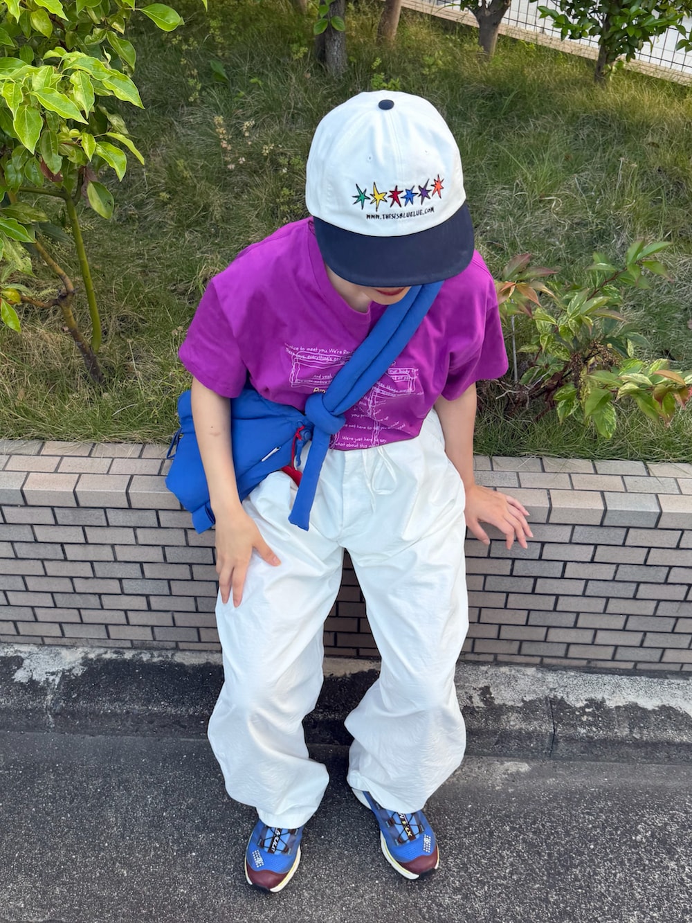 ブルー系のハンドバッグ、パープル系のTシャツ/カットソー、ホワイト系のパンツを着用したレディースの夏コーディネートの3枚目の写真