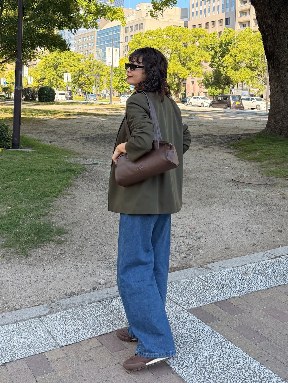グリーン系のジャケット/アウター、ブラウン系のショルダーバッグ、ホワイト系のTシャツ/カットソーを着用したレディースの秋コーディネートの3枚目の写真