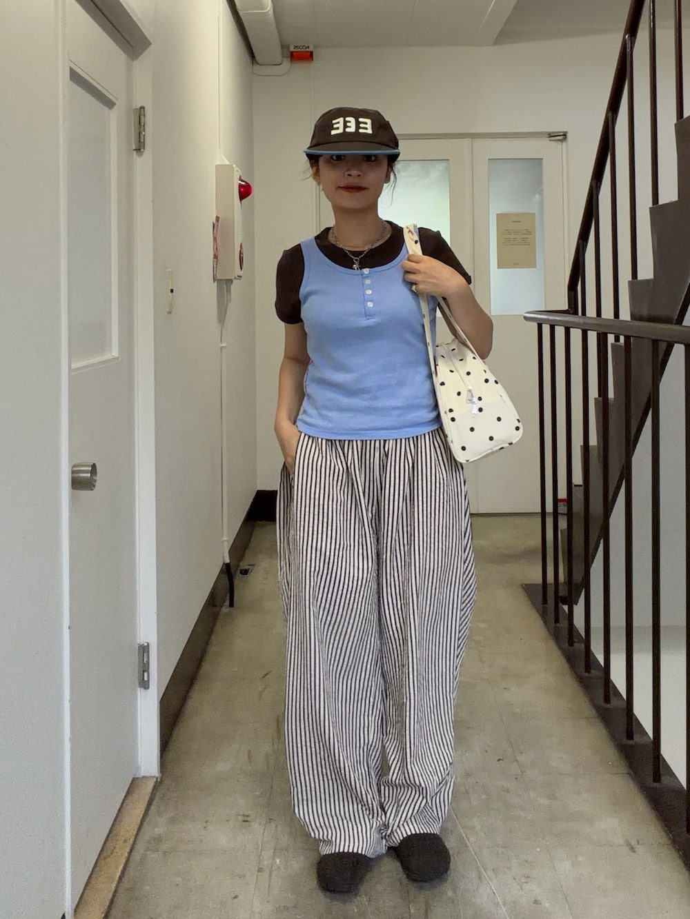 ブルー系のタンクトップ、ホワイト系のボストンバッグ、ホワイト系のパンツを着用したレディースの夏コーディネートの3枚目の写真