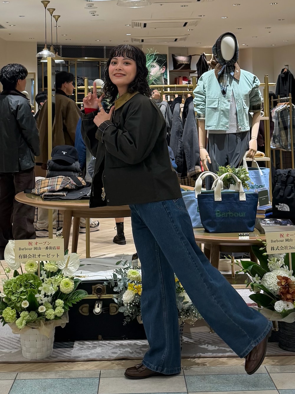 グリーン系のブルゾン、レッド系のトップス、ブルー系のデニムパンツを着用したレディースの秋コーディネートの3枚目の写真