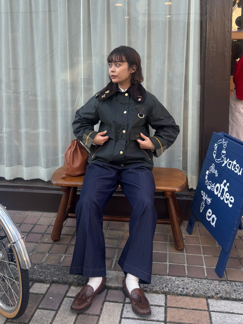 グリーン系のブルゾン、ブラウン系のバッグ、ブルー系のデニムパンツを着用したレディースの冬コーディネートの2枚目の写真