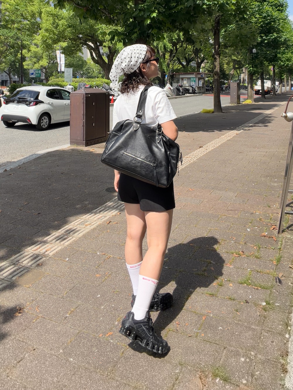 ブラック系のスニーカー、ブラック系のパンツ、ブラック系のバッグを着用したレディースの夏コーディネートの2枚目の写真