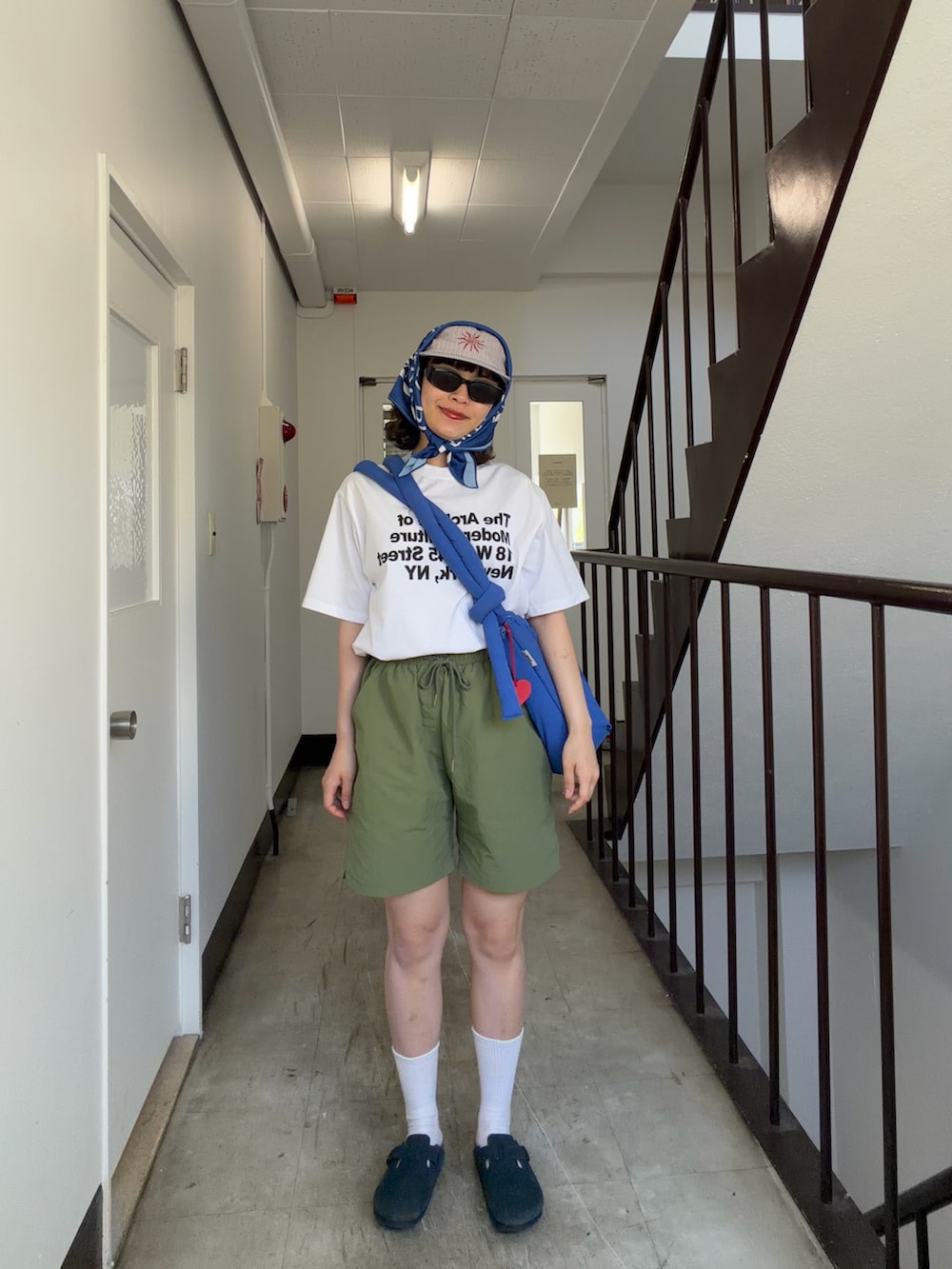 ホワイト系のTシャツ/カットソー、グリーン系のパンツ、ブルー系のサンダルを着用したレディースの春コーディネートの2枚目の写真