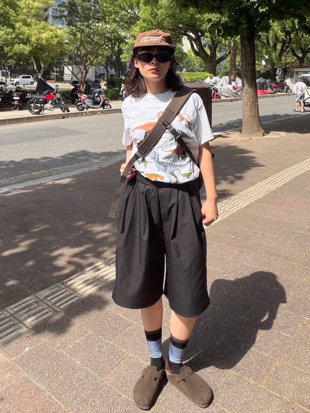 ブラウン系のショルダーバッグ、シルバー系のTシャツ/カットソー、ブラック系のパンツを着用したレディースの夏コーディネートの2枚目の写真