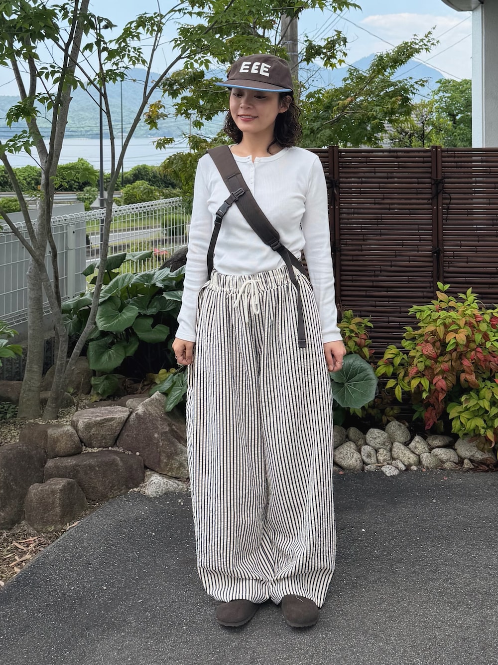 ホワイト系のパンツ、ホワイト系のトップス、ブラウン系のショルダーバッグを着用したレディースの春コーディネートの2枚目の写真