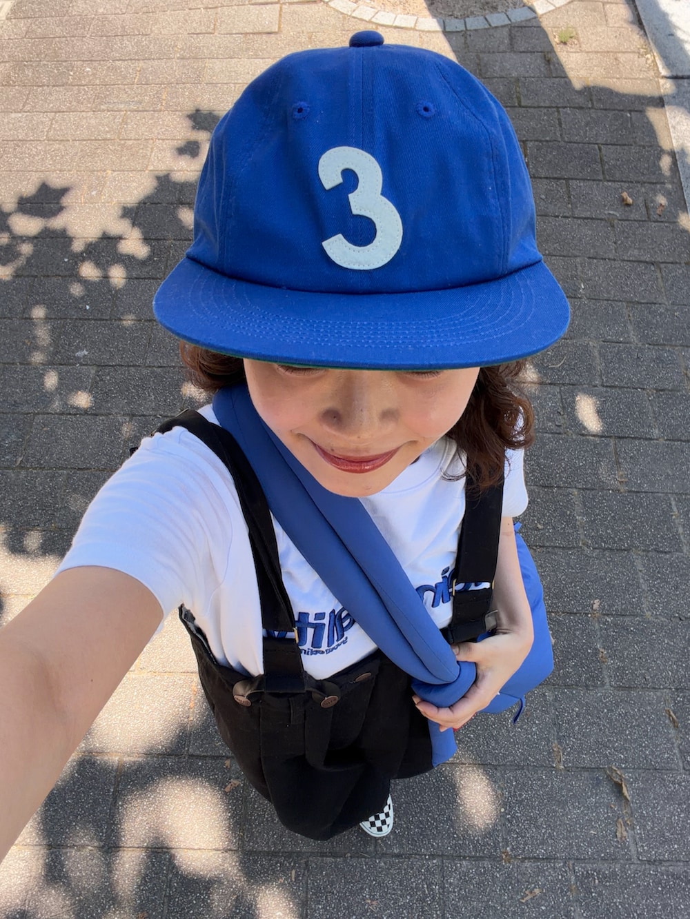 ブルー系のハンドバッグ、ホワイト系のTシャツ/カットソー、ブラック系のチノパンツを着用したレディースの夏コーディネートの3枚目の写真