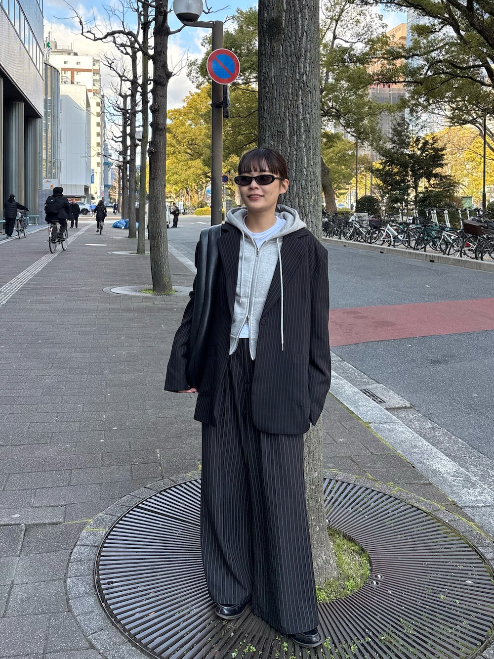 グレー系のパーカー、ブラック系のテーラードジャケット、ブラック系のスラックスを着用したレディースの冬コーディネートの2枚目の写真