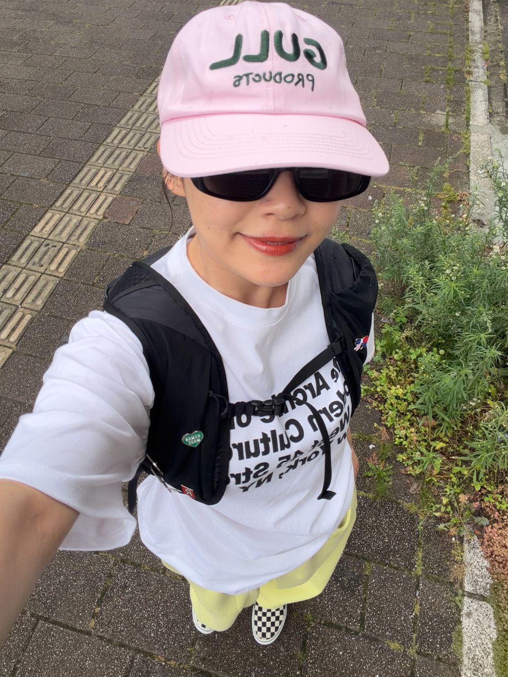 ホワイト系のTシャツ/カットソー、ブラック系のバックパック/リュック、イエロー系のスウェットパンツを着用したレディースの夏コーディネートの3枚目の写真
