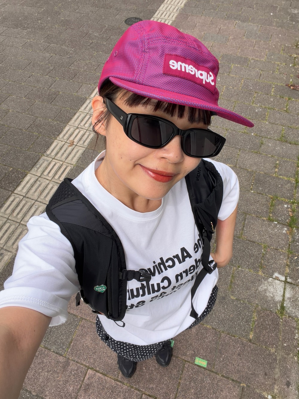 ブラック系のスニーカー、ブラック系のバックパック/リュック、ホワイト系のTシャツ/カットソーを着用したレディースの夏コーディネートの4枚目の写真