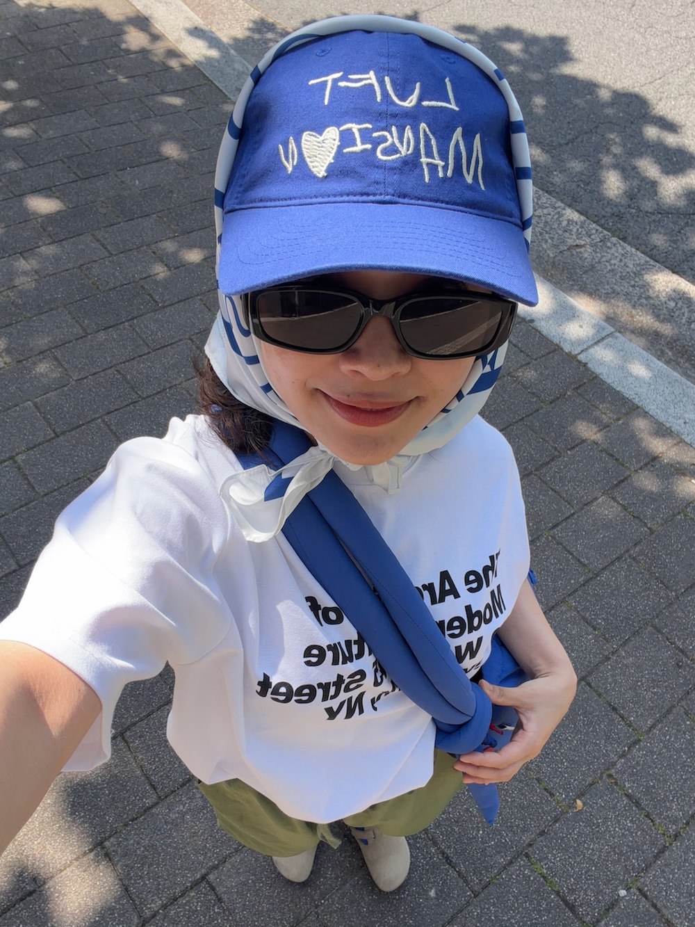 ブルー系のハンドバッグ、ホワイト系のTシャツ/カットソー、グリーン系のパンツを着用したレディースの春コーディネートの3枚目の写真