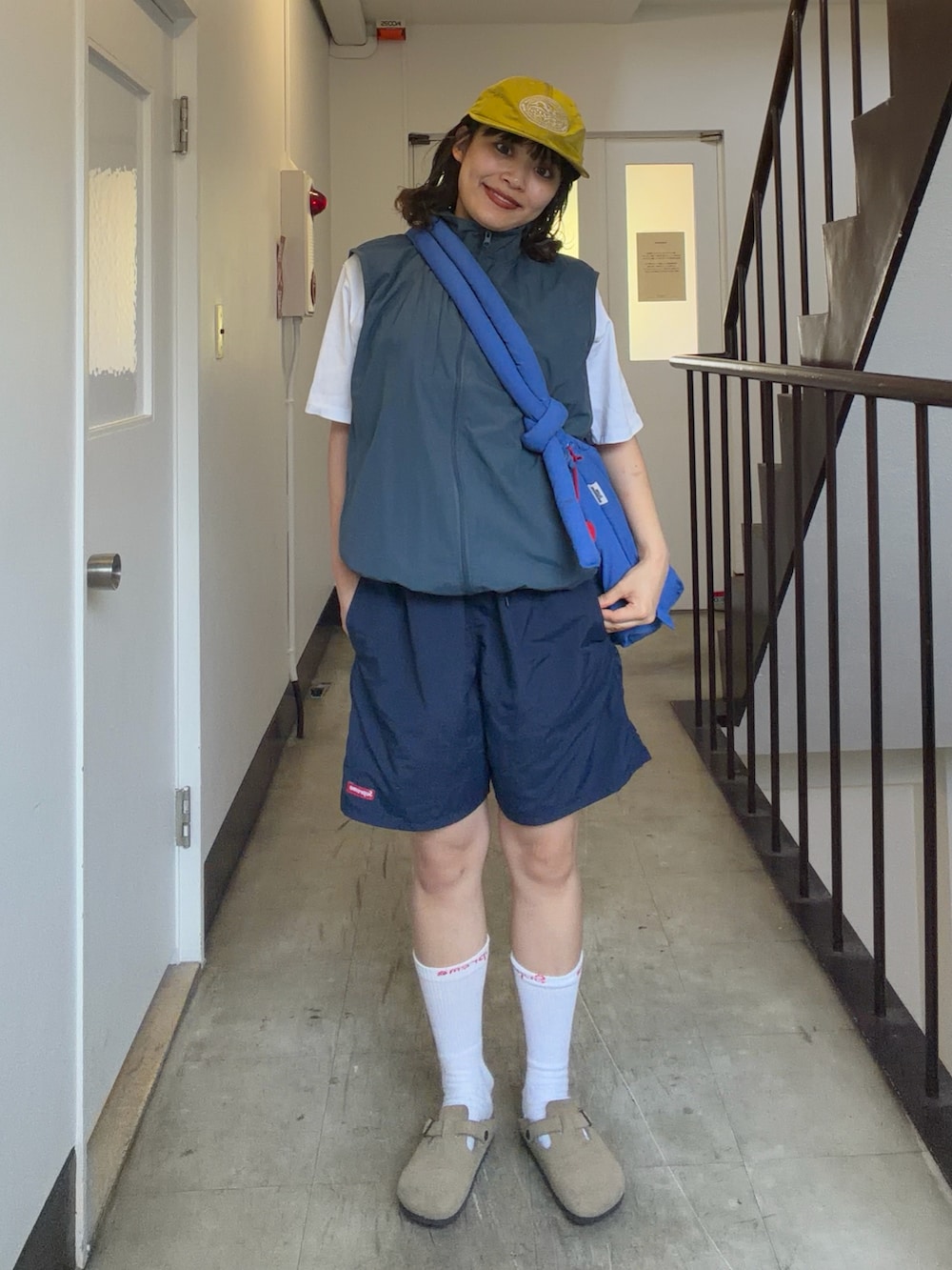 ブルー系のハンドバッグ、ベージュ系のサンダル、ブルー系のトップスを着用したレディースの夏コーディネートの2枚目の写真