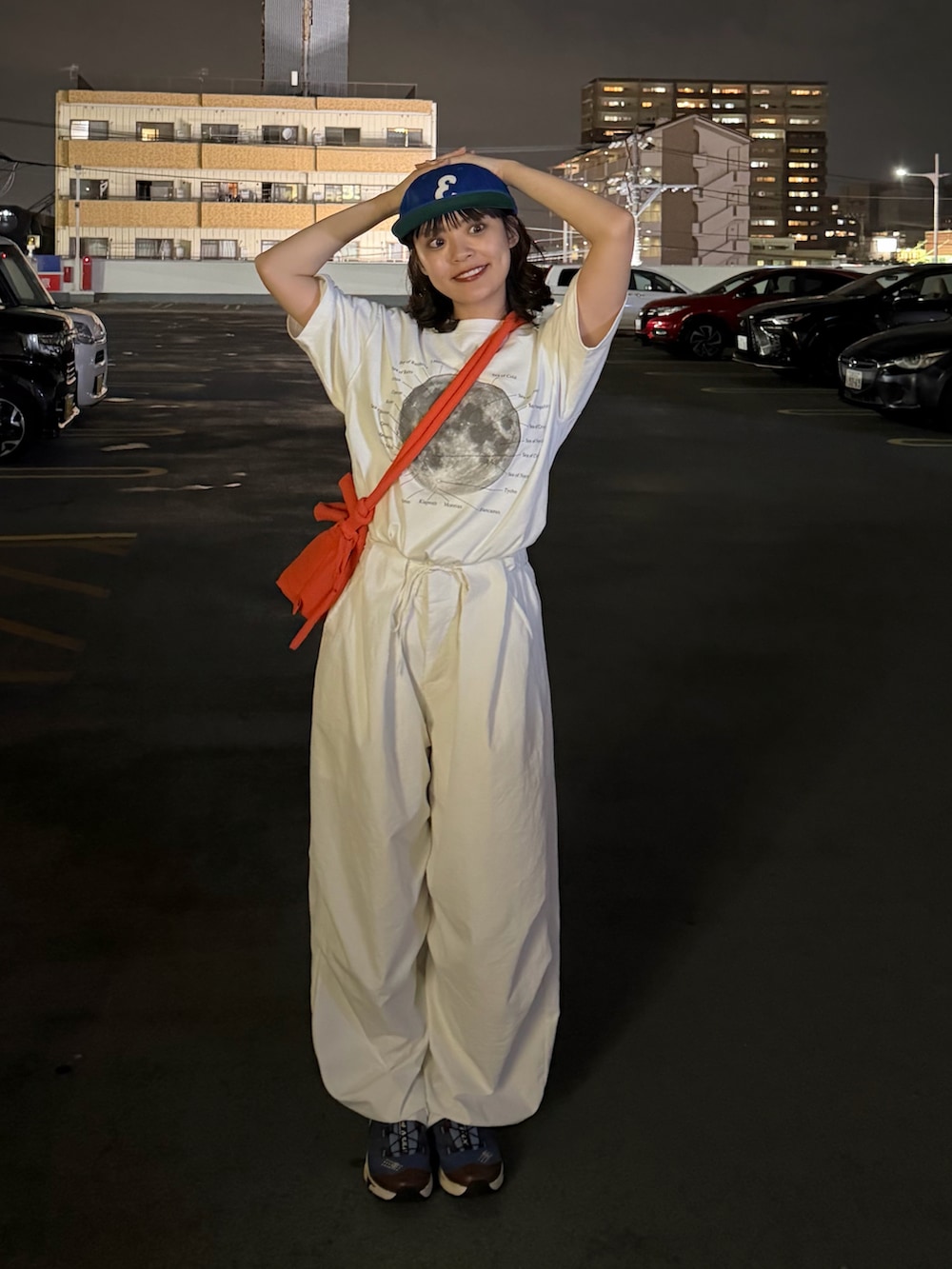 ホワイト系のTシャツ/カットソー、オレンジ系のハンドバッグ、ホワイト系のパンツを着用したレディースの夏コーディネートの2枚目の写真
