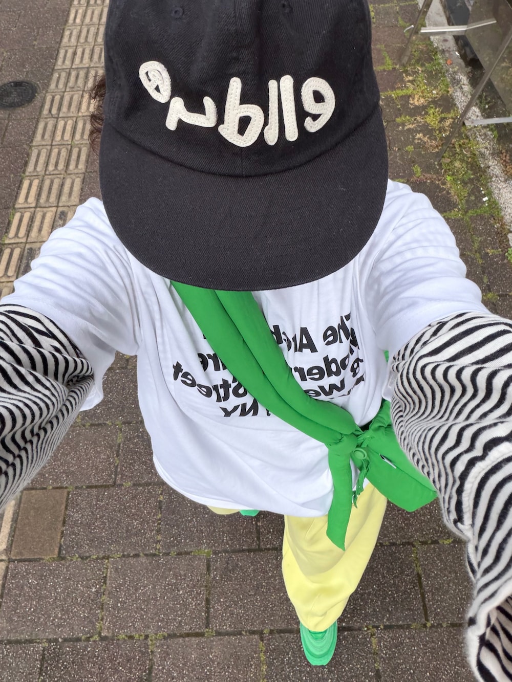 イエロー系のスウェットパンツ、グリーン系のスニーカー、グリーン系のハンドバッグを着用したレディースの春コーディネートの3枚目の写真