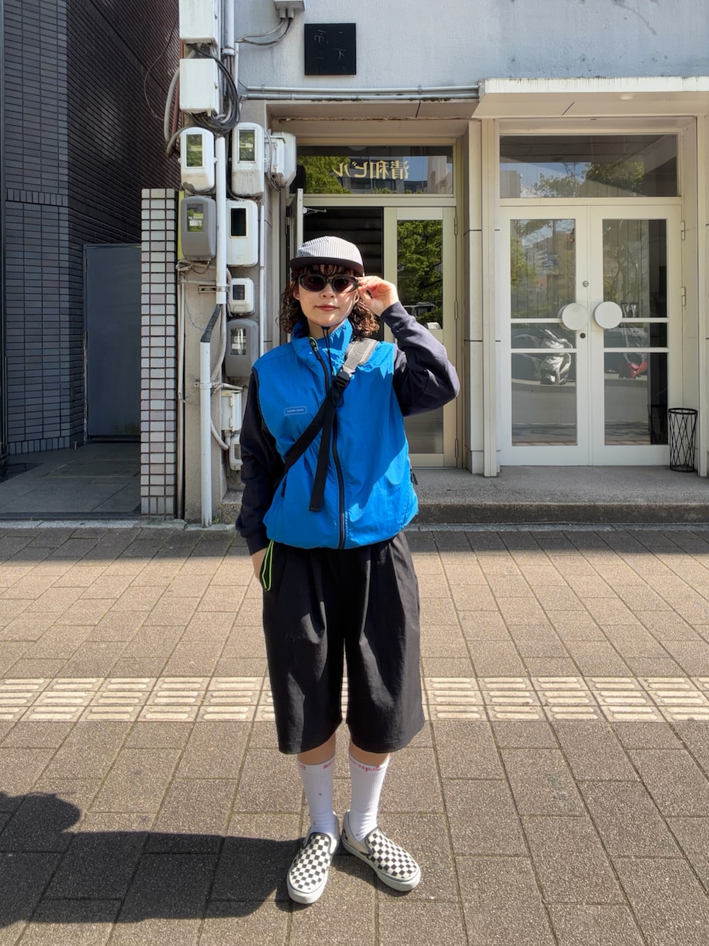 ブルー系のベスト、ブラック系のパンツ、ブラック系のスリッポンを着用したレディースの春コーディネートの2枚目の写真
