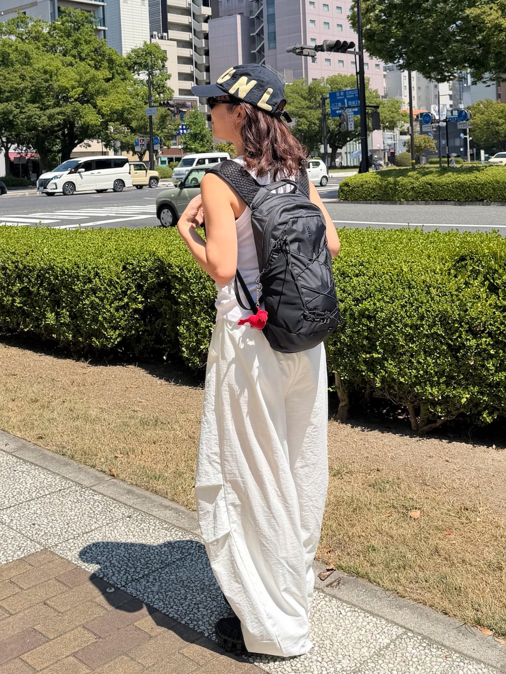 ブラック系のスニーカー、ブラック系のバックパック/リュック、ホワイト系のタンクトップを着用したレディースの夏コーディネートの2枚目の写真