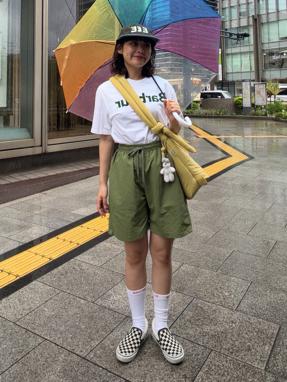 イエロー系のハンドバッグ、グリーン系のパンツ、ブラック系のスリッポンを着用したレディースの夏コーディネートの2枚目の写真