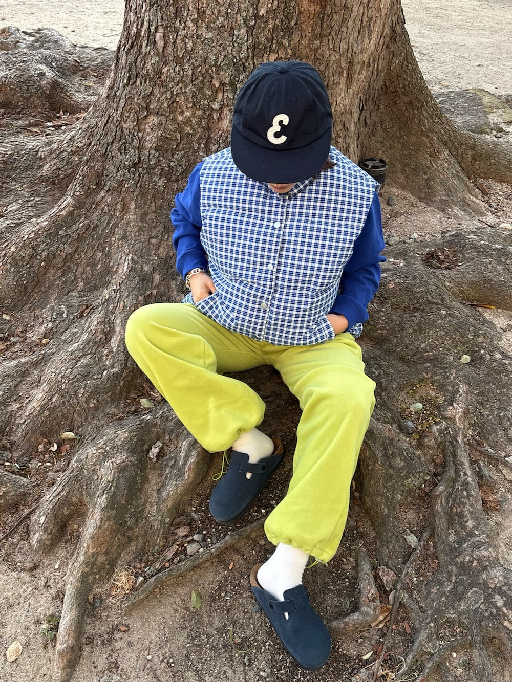 グリーン系のパンツ、ブルー系のダウンベスト、ブルー系のサンダルを着用したレディースの冬コーディネートの2枚目の写真