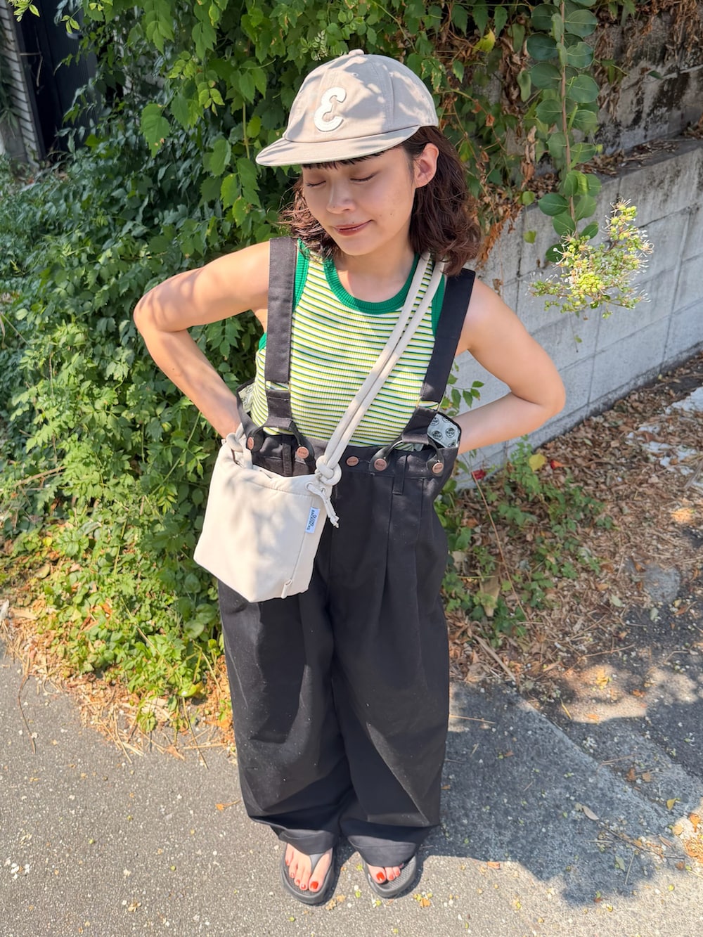 グリーン系のタンクトップ、ブラック系のチノパンツ、ブラック系のサンダルを着用したレディースの夏コーディネートの3枚目の写真