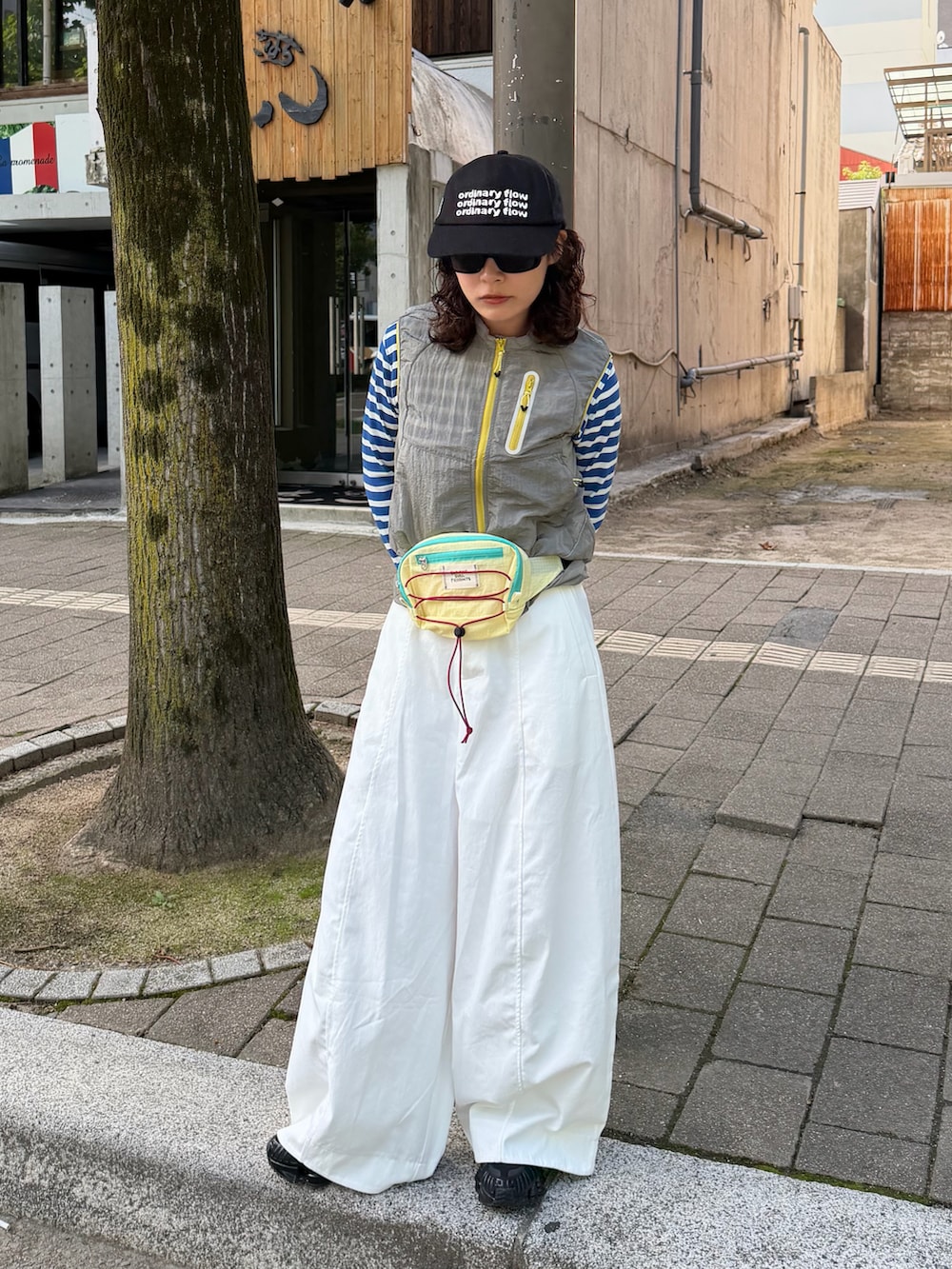 ブラック系のスニーカー、イエロー系のボディバッグ/ウエストポーチ、グレー系のトップスを着用したレディースの秋コーディネートの2枚目の写真