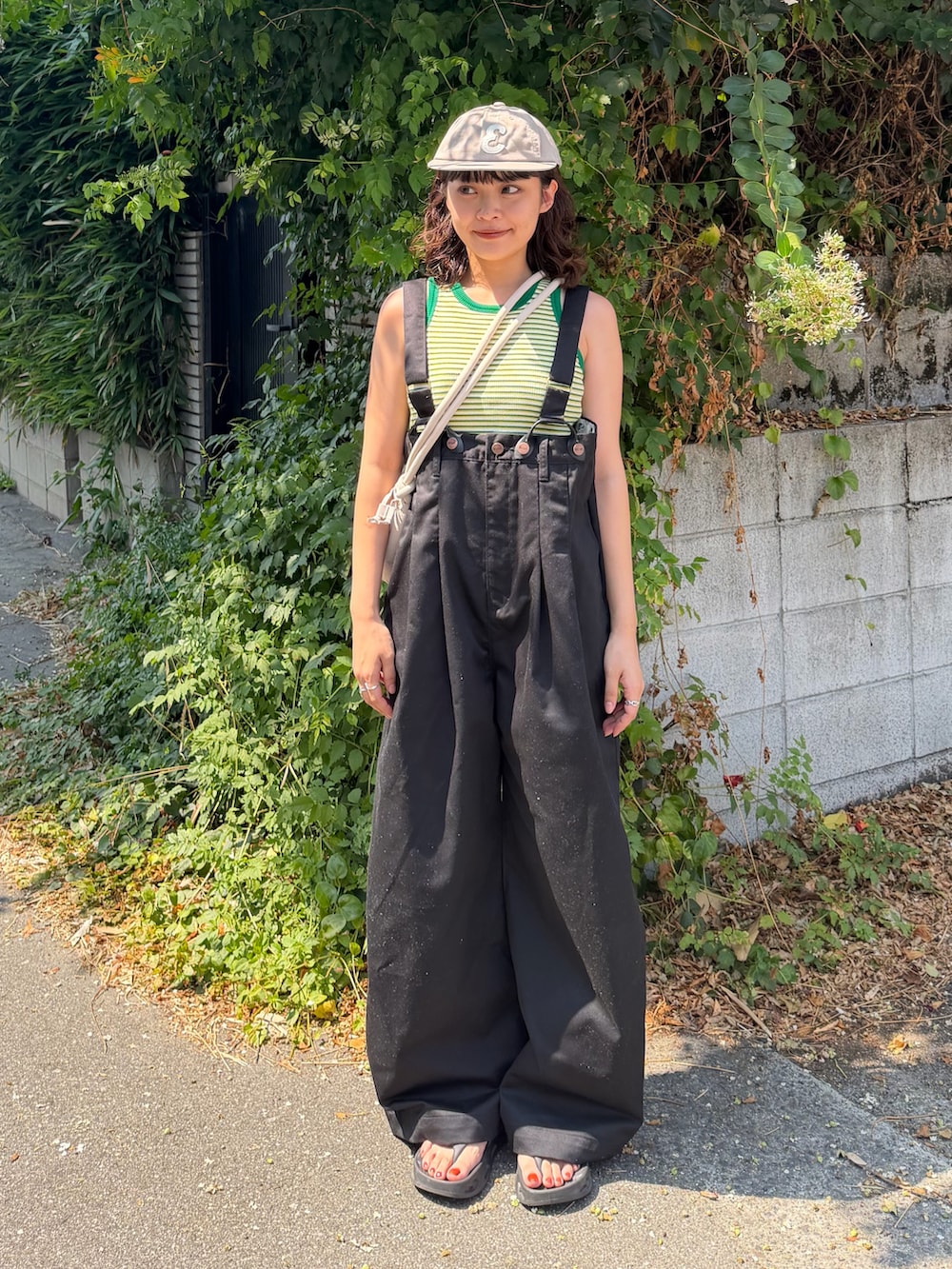 グリーン系のタンクトップ、ブラック系のチノパンツ、ブラック系のサンダルを着用したレディースの夏コーディネートの2枚目の写真
