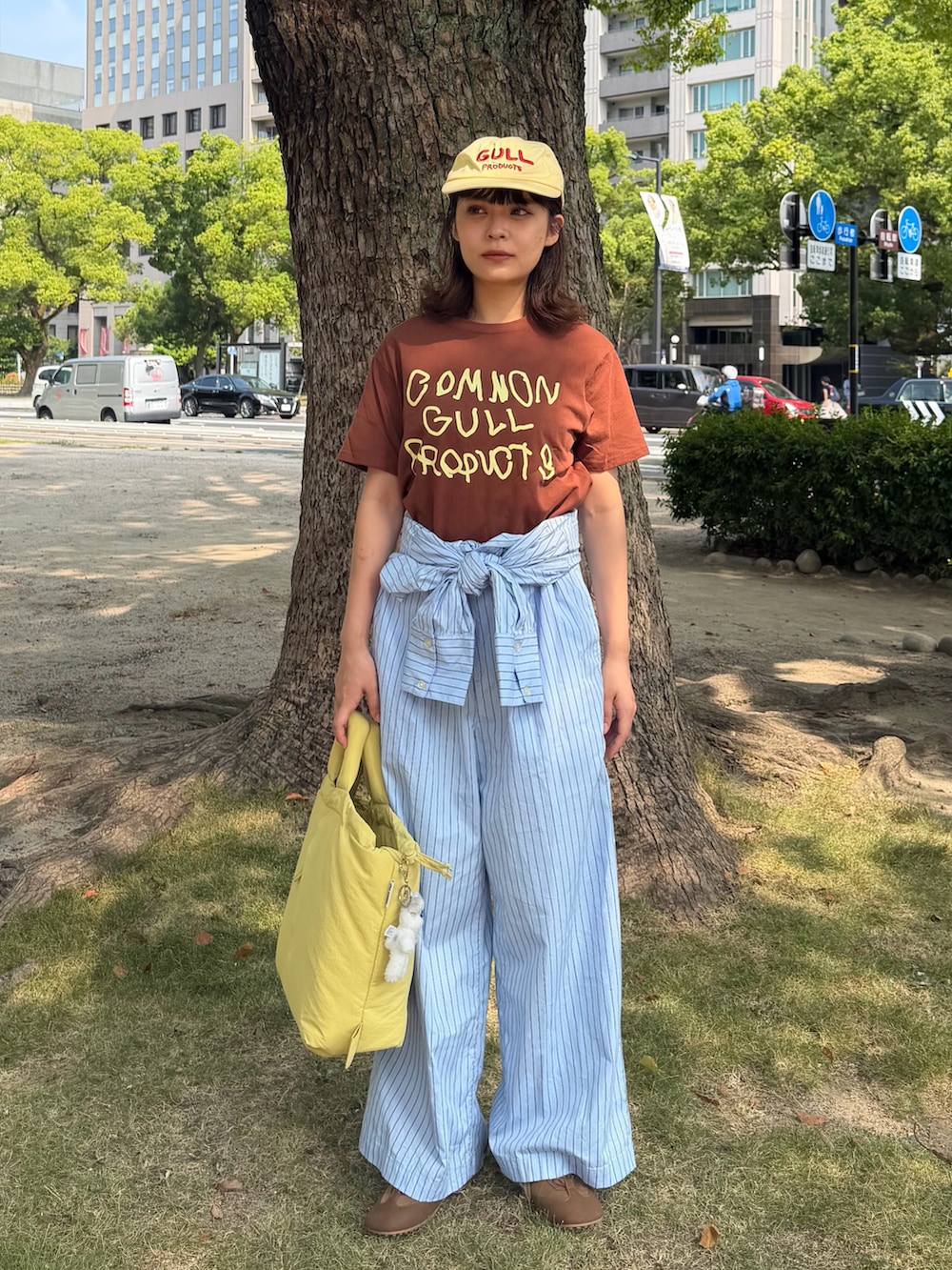 ブルー系のサロペット/オーバーオール、ブラウン系のTシャツ/カットソー、イエロー系のハンドバッグを着用したレディースの秋コーディネートの3枚目の写真
