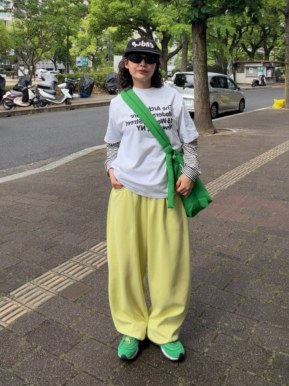 イエロー系のスウェットパンツ、グリーン系のスニーカー、グリーン系のハンドバッグを着用したレディースの春コーディネートの2枚目の写真