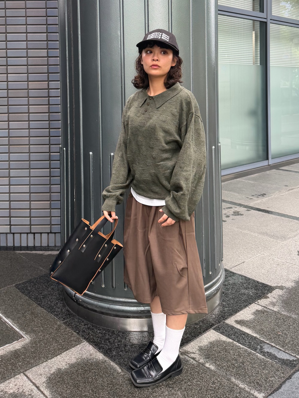 グリーン系のニット/セーター、ブラウン系のパンツ、ブラック系のハンドバッグを着用したレディースの秋コーディネートの2枚目の写真