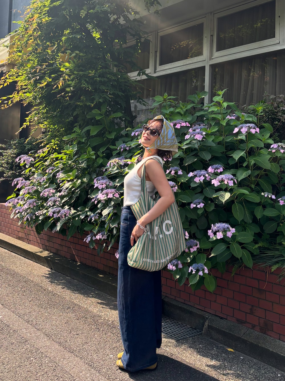 グリーン系のバッグ、ブルー系のデニムパンツ、ホワイト系のトップスを着用したレディースの夏コーディネートの2枚目の写真