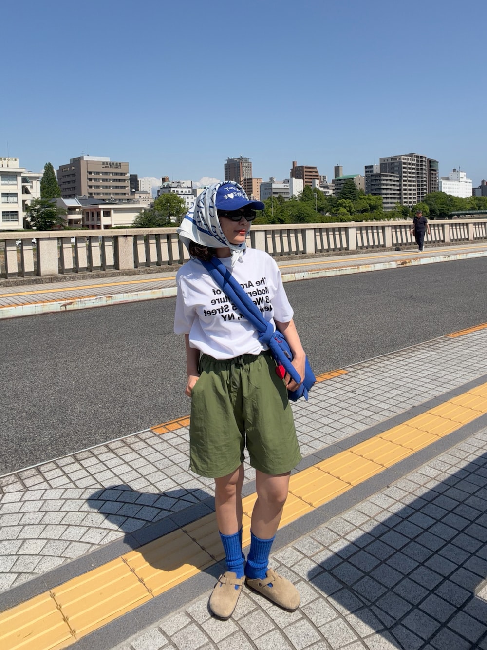 ブルー系のハンドバッグ、ホワイト系のTシャツ/カットソー、グリーン系のパンツを着用したレディースの春コーディネートの2枚目の写真