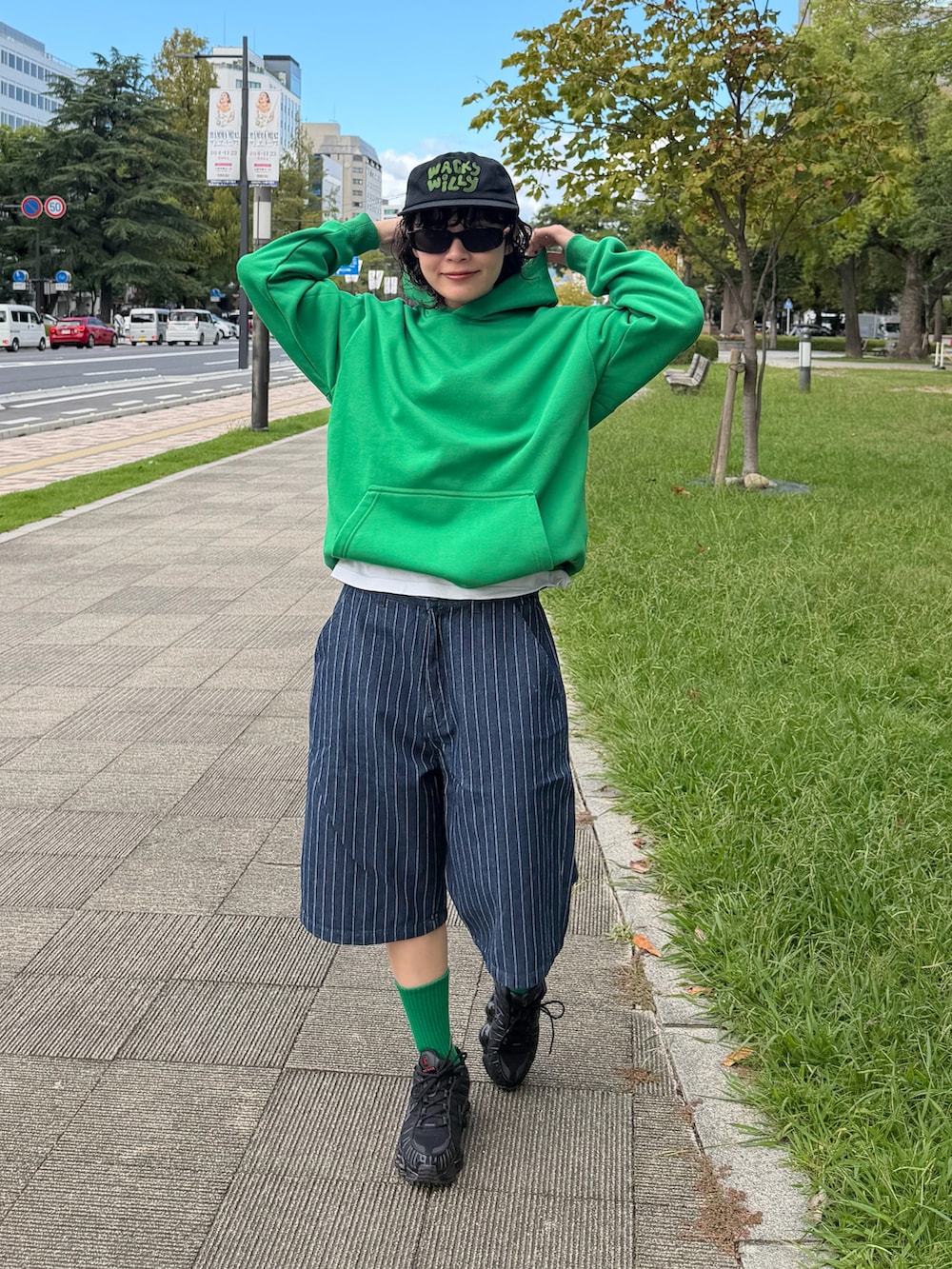 ブラック系のスニーカー、ブルー系のデニムパンツ、グリーン系のトップスを着用したレディースの秋コーディネートの2枚目の写真