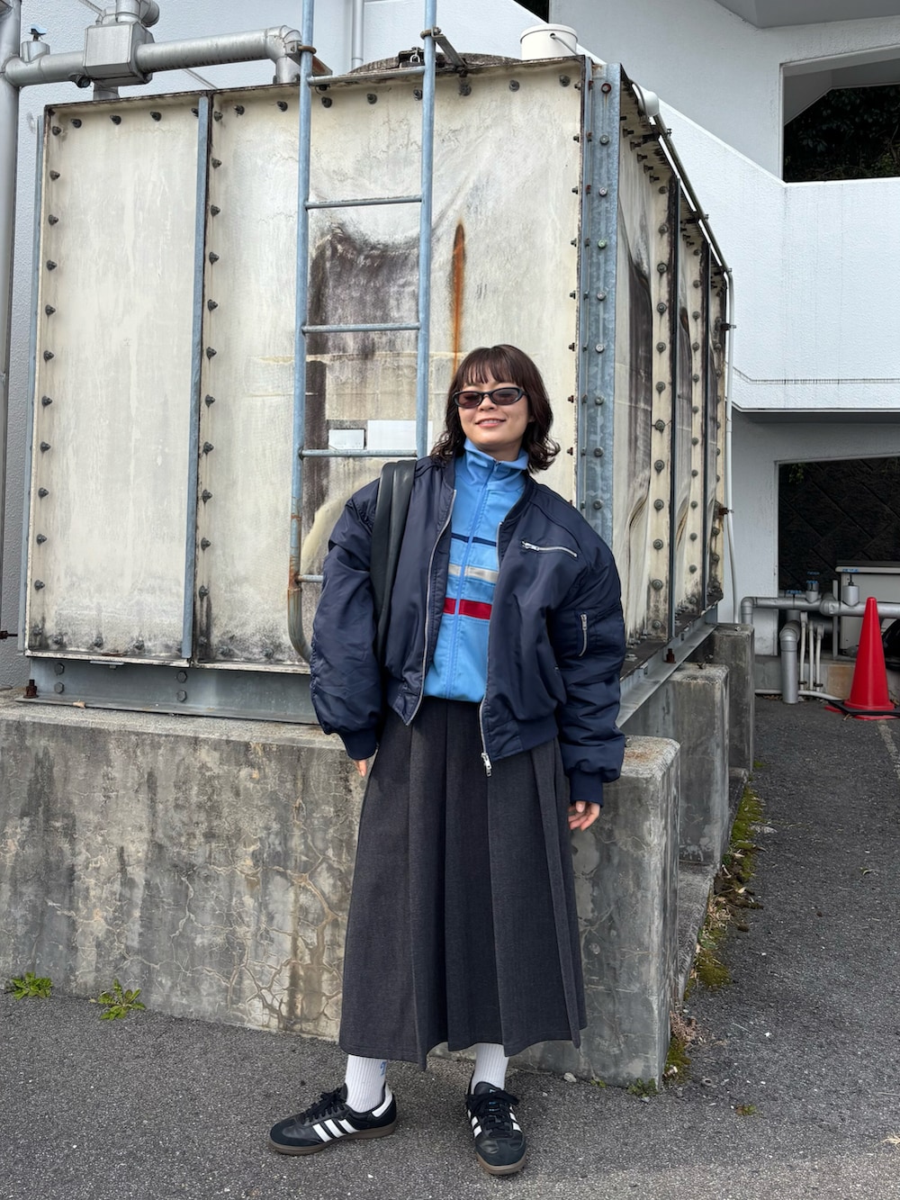 ブラック系のバッグ、グレー系のスカート、ブラック系のスニーカーを着用したレディースの冬コーディネートの3枚目の写真