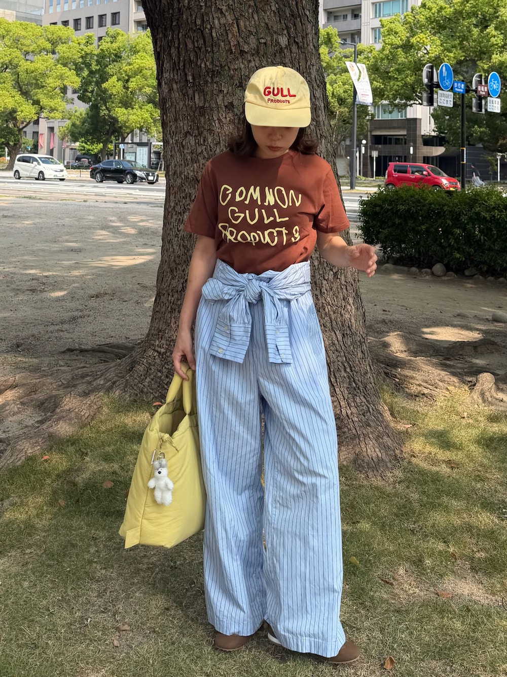 ブルー系のサロペット/オーバーオール、ブラウン系のTシャツ/カットソー、イエロー系のハンドバッグを着用したレディースの秋コーディネートの2枚目の写真
