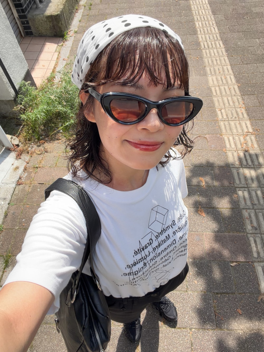 ブラック系のスニーカー、ブラック系のパンツ、ブラック系のバッグを着用したレディースの夏コーディネートの3枚目の写真