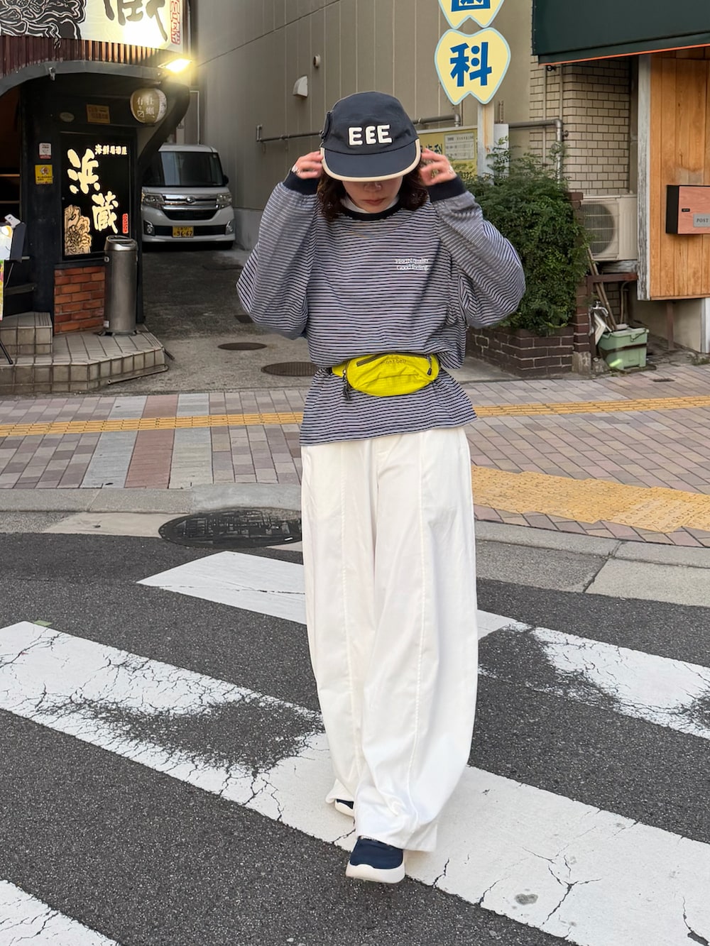 ブルー系のTシャツ/カットソー、イエロー系のバッグ、ホワイト系のパンツを着用したレディースの秋コーディネートの2枚目の写真