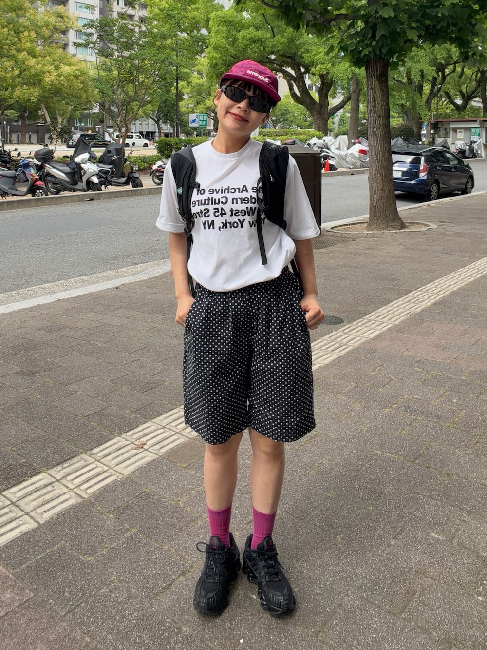 ブラック系のスニーカー、ブラック系のバックパック/リュック、ホワイト系のTシャツ/カットソーを着用したレディースの夏コーディネートの2枚目の写真