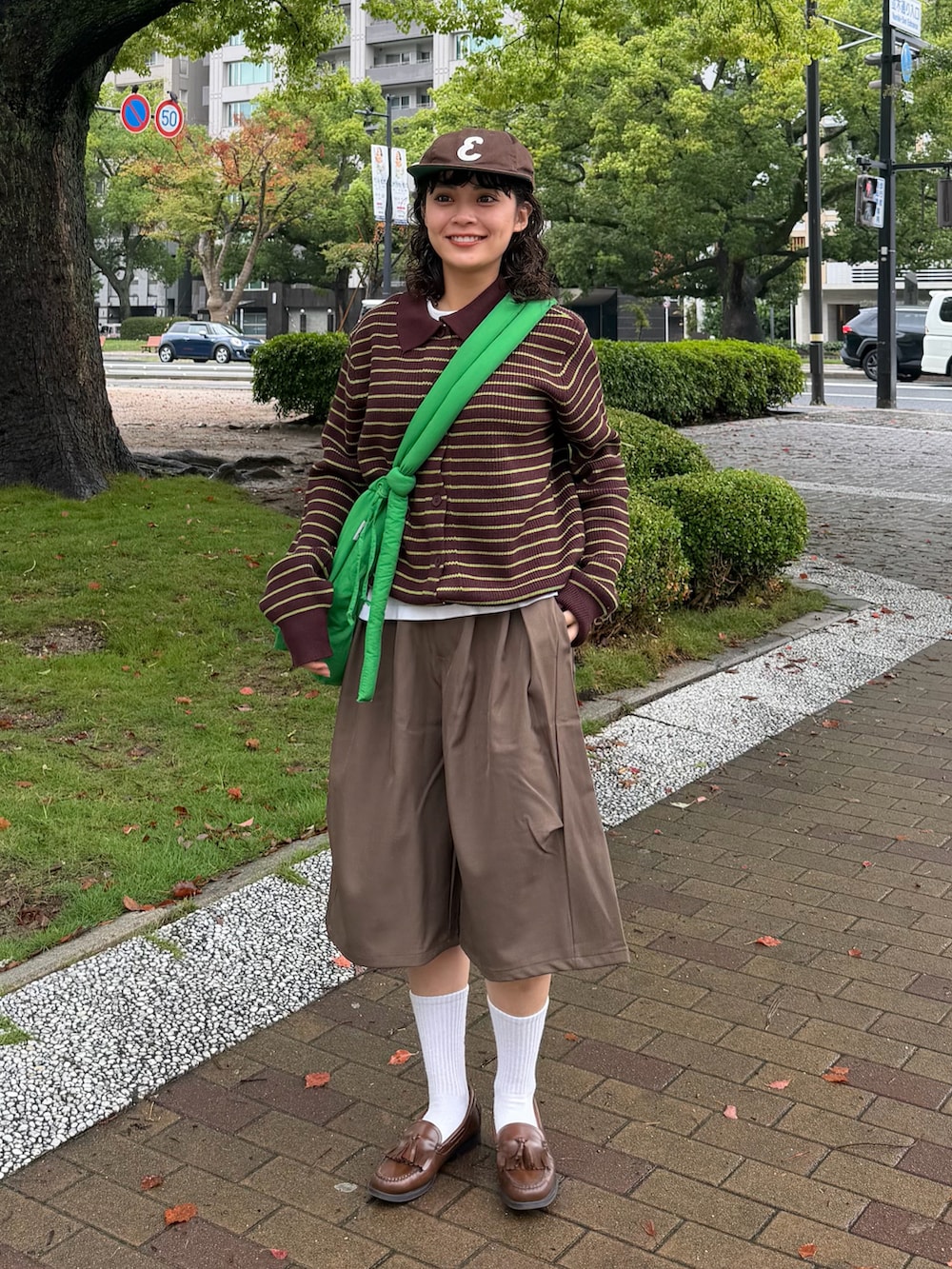 ブラウン系のニット/セーター、グリーン系のハンドバッグ、ブラウン系のローファーを着用したレディースの秋コーディネートの2枚目の写真