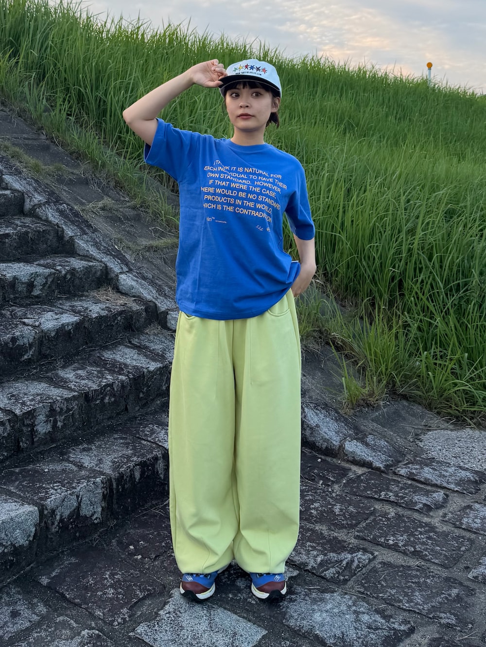 ブルー系のTシャツ/カットソー、イエロー系のスウェットパンツ、ブルー系のシューズを着用したレディースの夏コーディネートの2枚目の写真