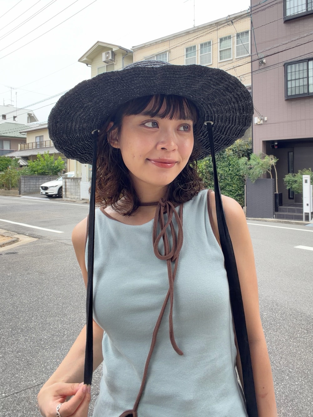 ブルー系のタンクトップ、ブラック系のパンツ、ブラック系のハンドバッグを着用したレディースの夏コーディネートの3枚目の写真