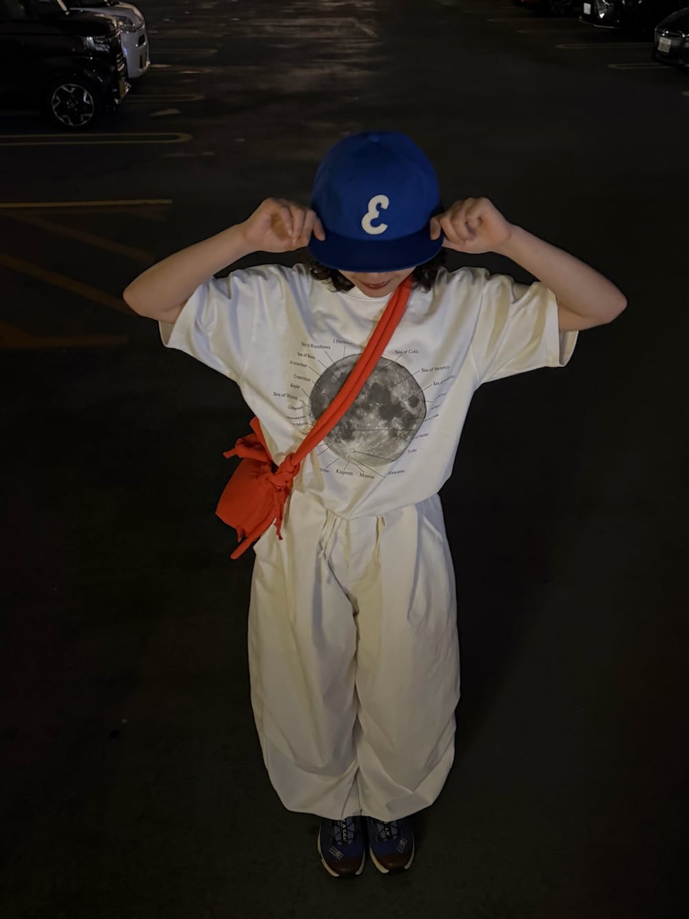 ホワイト系のTシャツ/カットソー、オレンジ系のハンドバッグ、ホワイト系のパンツを着用したレディースの夏コーディネートの3枚目の写真