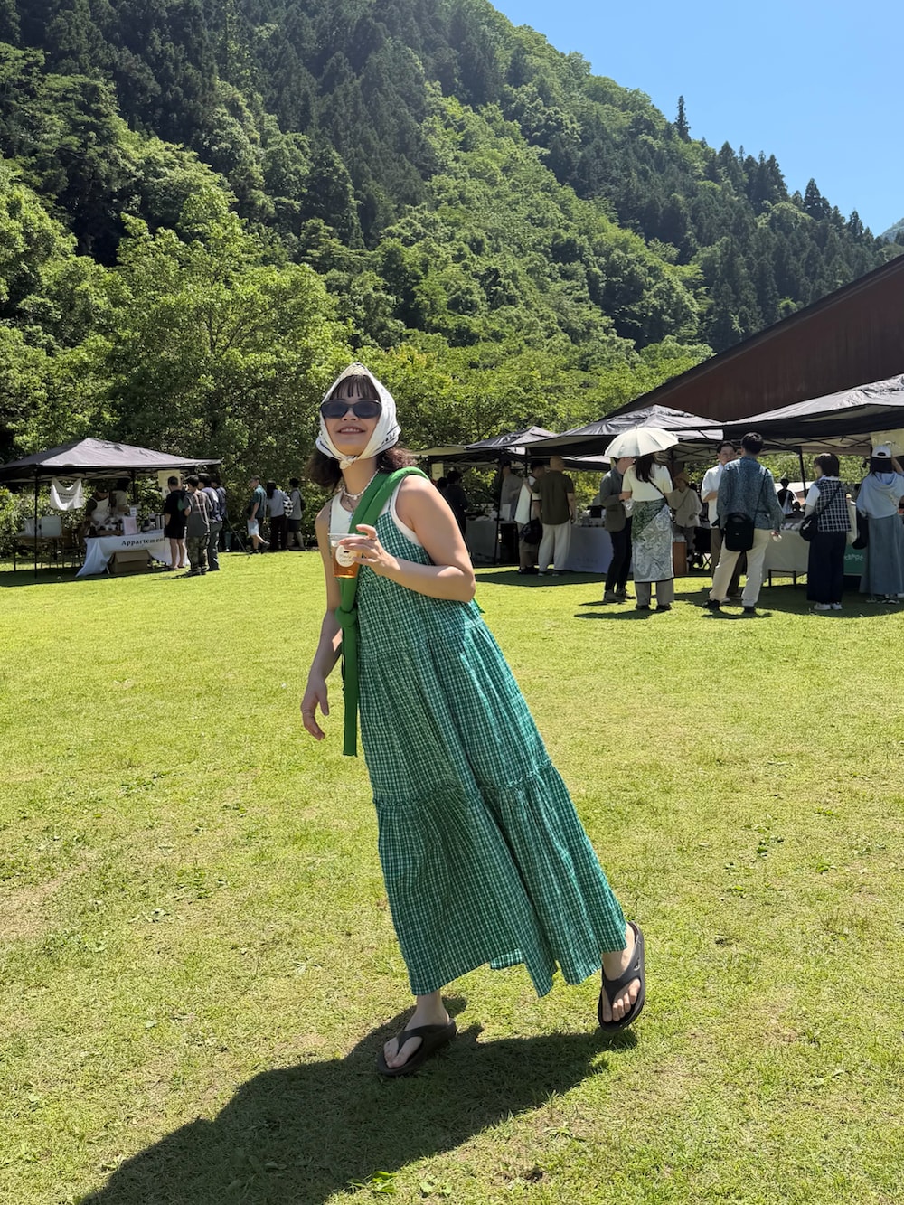 グリーン系のハンドバッグ、ブラック系のサンダル、グリーン系のワンピース/ドレスを着用したレディースの春コーディネートの2枚目の写真