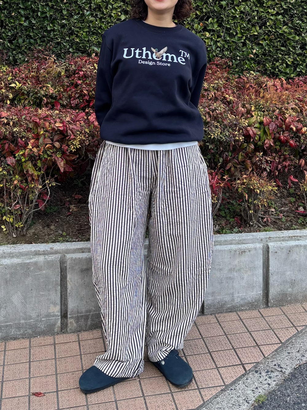 ブルー系のスウェット、ホワイト系のパンツ、ブルー系のサンダルを着用したレディースの春コーディネートの2枚目の写真