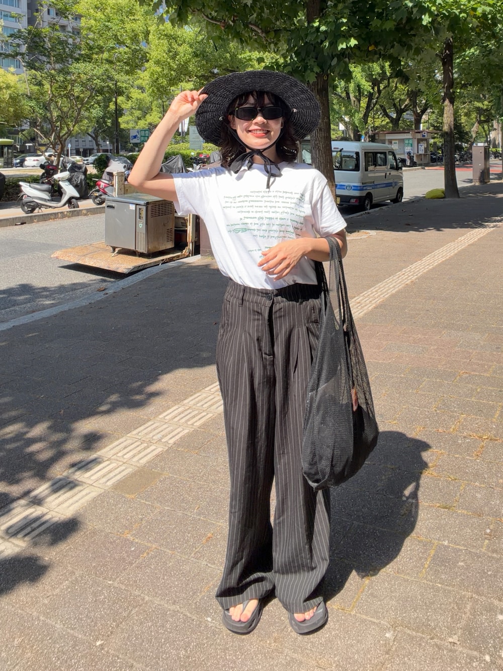 ホワイト系のTシャツ/カットソー、ブラック系のスラックス、ブラック系のバッグを着用したレディースの夏コーディネートの2枚目の写真