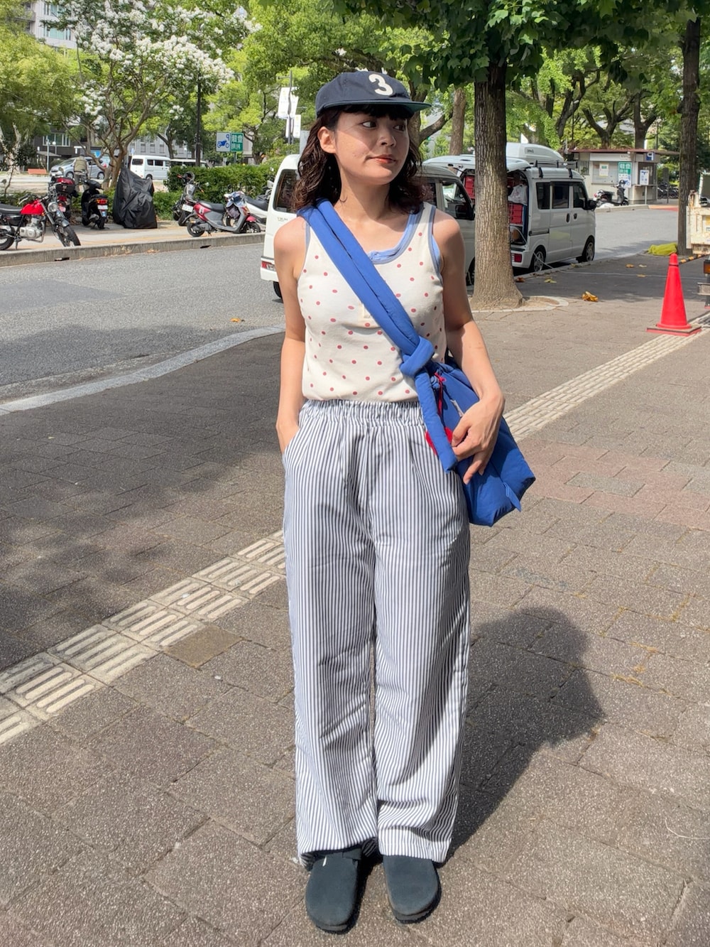 レッド系のタンクトップ、ブルー系のハンドバッグ、ホワイト系のパンツを着用したレディースの夏コーディネートの3枚目の写真