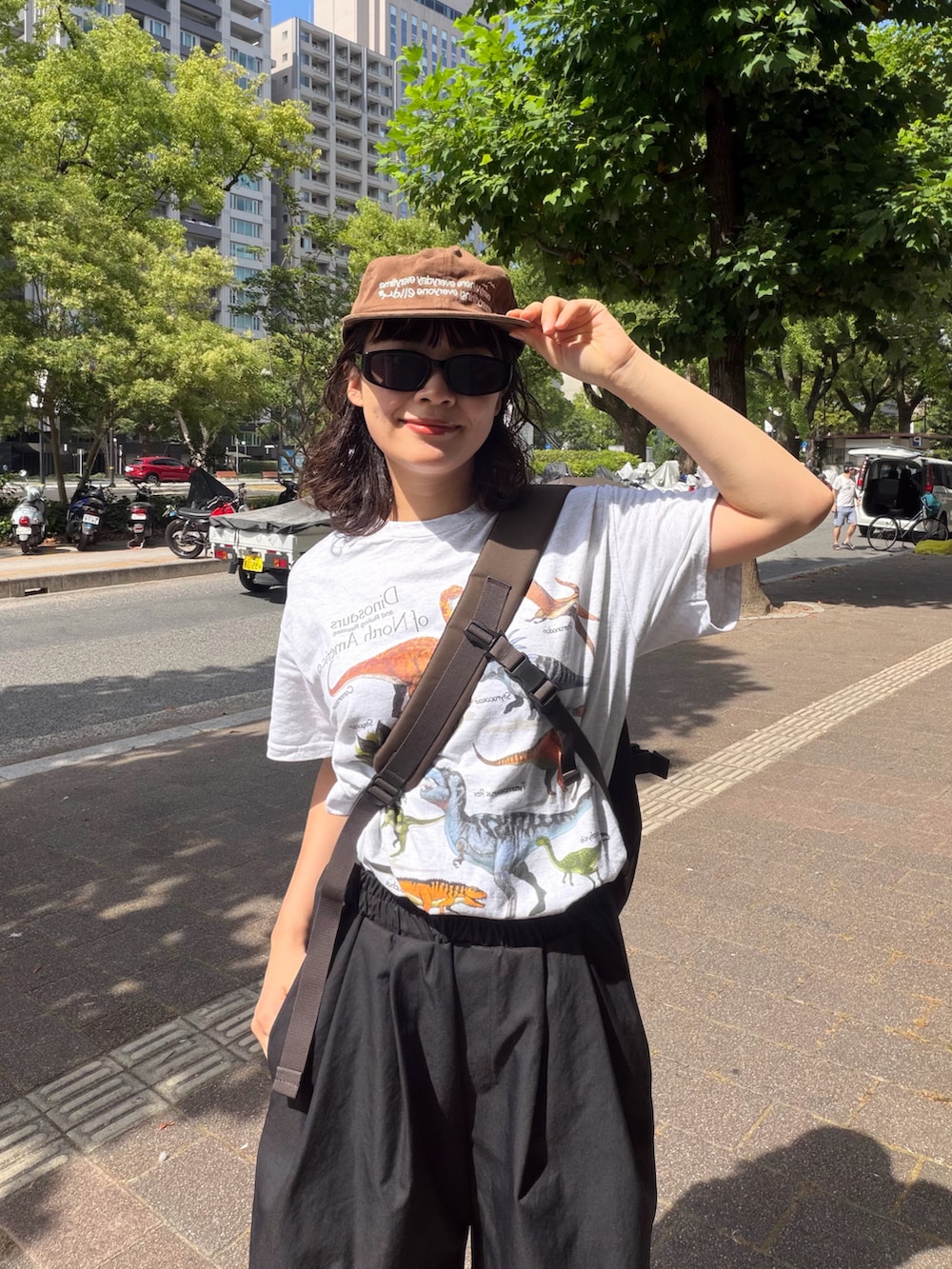 ブラウン系のショルダーバッグ、シルバー系のTシャツ/カットソー、ブラック系のパンツを着用したレディースの夏コーディネートの3枚目の写真