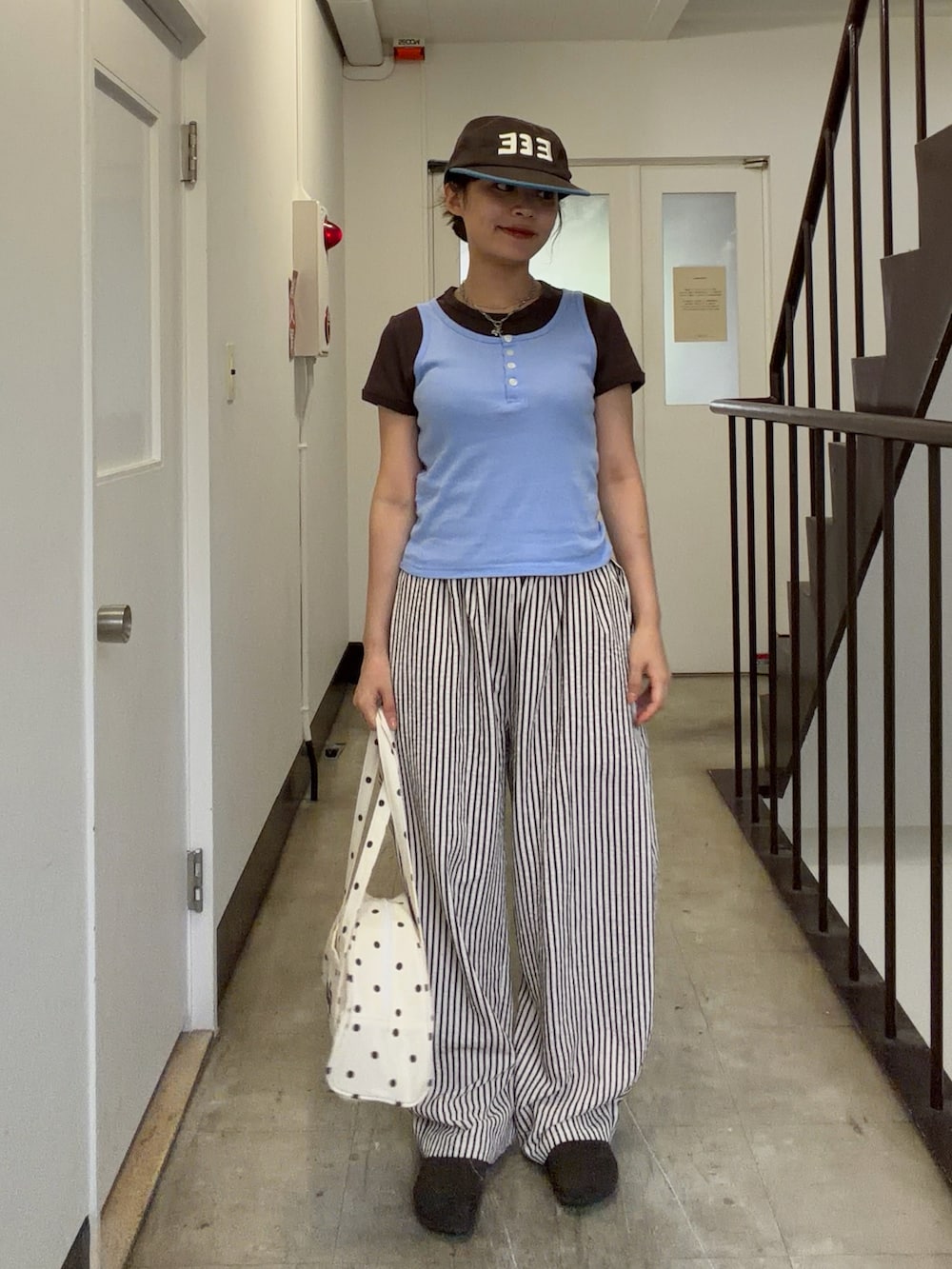ブルー系のタンクトップ、ホワイト系のボストンバッグ、ホワイト系のパンツを着用したレディースの夏コーディネートの2枚目の写真
