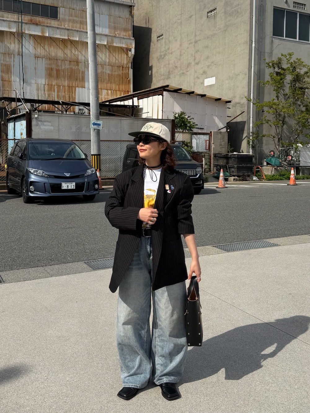 ブラック系のハンドバッグ、ホワイト系のTシャツ/カットソー、ブラック系のジャケット/アウターを着用したレディースの春コーディネートの2枚目の写真