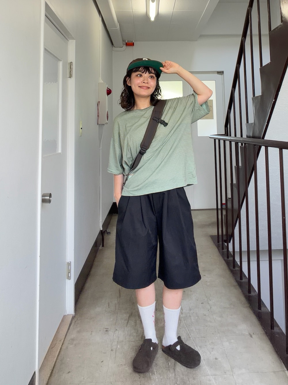 グリーン系のTシャツ/カットソー、ブラック系のパンツ、ブラウン系のサンダルを着用したレディースの夏コーディネートの2枚目の写真