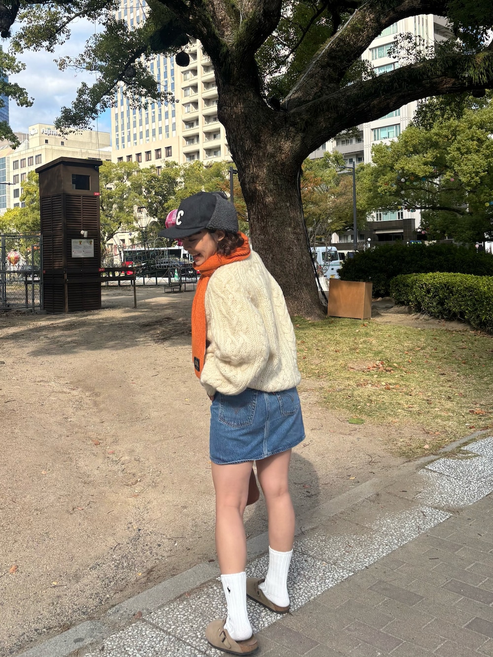 ブラウン系のサンダル、ブルー系のデニムスカート、ベージュ系のニット/セーターを着用したレディースの冬コーディネートの2枚目の写真